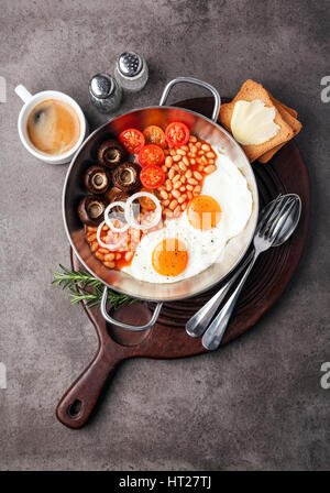 Full English Breakfast with fried eggs, beans, toasts, tomatoes , mushrooms and coffee on grey background Stock Photo