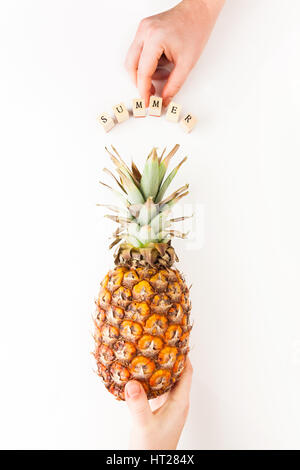 Female hand holding ripe pineapple on a white background Stock Photo