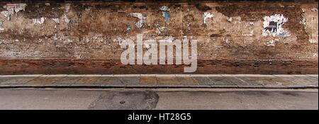 Brick wall and sidewalk in an urban environment Stock Photo