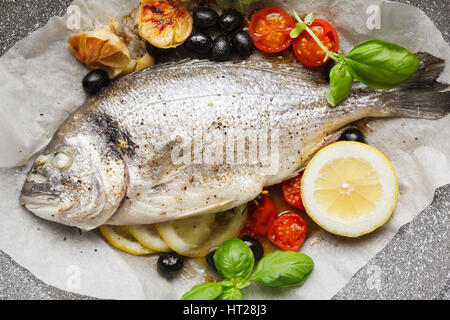 fish gilt-head Bram, cooked in a pan with vegetables and lemon, black olives. fresh basil . Healthy lunch Stock Photo