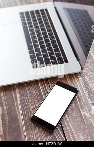 mobile and laptop on wood desk selective focus on phone white blank screen vertical view Stock Photo