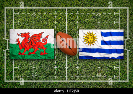 Wales vs. Uruguay flags on green rugby field Stock Photo