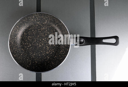 Frying pan on the glass substrate in the kitchen, top view Stock Photo