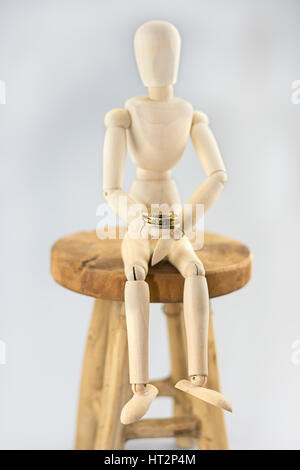 Mannequin sitting on a chair and holding a coin. Stock Photo