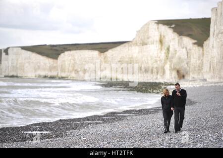 Birling Gap, East Sussex, UK. 6th March 2017. UK Weather. A couple enjoying a stoll along the beach below the Seven Sisters chalk cliffs in the South Downs national park as temperatures reach double figure. Credit: Peter Cripps/Alamy Live News Stock Photo