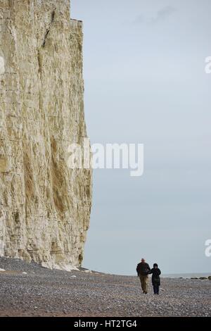 Birling Gap, East Sussex, UK. 6th March 2017. UK Weather. A couple enjoying a stoll along the beach below the Seven Sisters chalk cliffs in the South Downs national park as temperatures reach double figure. Credit: Peter Cripps/Alamy Live News Stock Photo