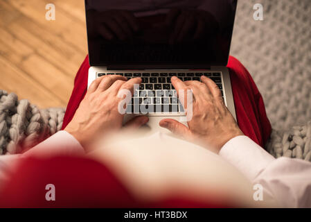 Santa Claus typing on laptop Stock Photo