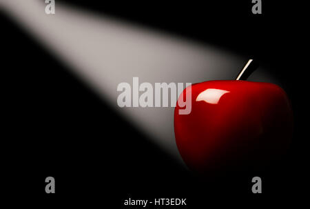 Red apple in a light beam on a black background. Stock Photo