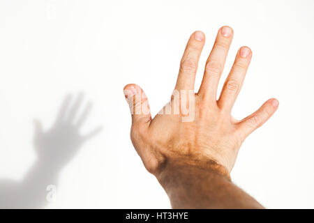 Male hand over white wall background with soft shadow, close up photo with selective focus Stock Photo