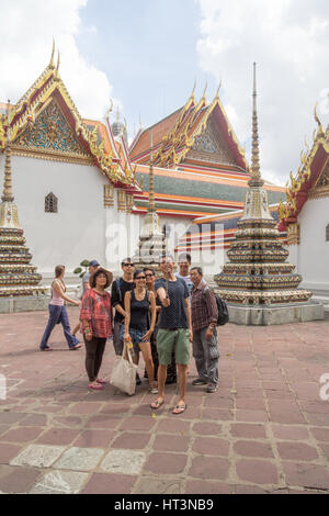 Tourists at Wat Pho Temple taking pictures of buddhist monks as they