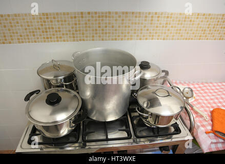 many large steel pots and small saucepan on the stove inside the restaurant during the preparation of food Stock Photo