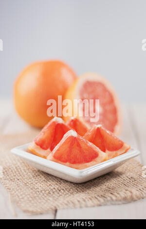 Sliced grapefruit on burlap fabric of whole and half in the background. Stock Photo