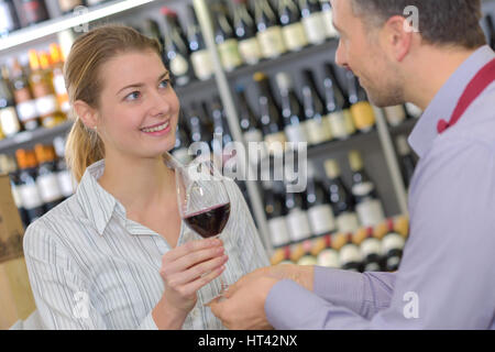 sommelier handing woman red wine to taste in wine shop Stock Photo