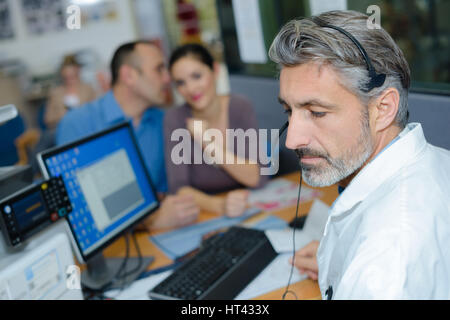 Husband whispering to wife during meeting Stock Photo