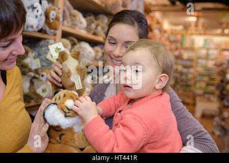 mother and daughter with attractive vendor in toy store Stock Photo