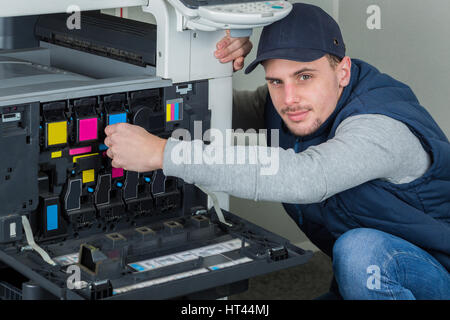 young male technician repairing digital photocopier printer machine Stock Photo