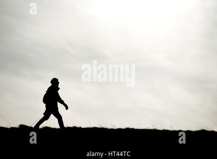 Silhouette of a woman walking a dog on a cloudy day Stock Photo