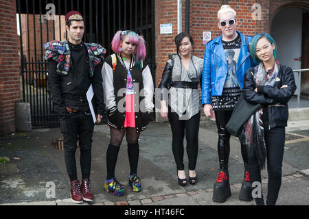 LONDON, ENGLAND - JULY 12, 2016 Fashionably-dressed group of young people standing near the wall. Stock Photo