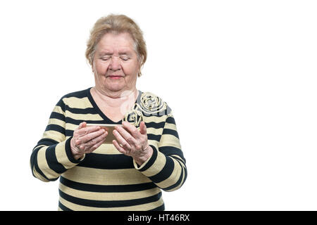Old woman holds a smartphone with two hands and looking at it, isolated on a white background Stock Photo