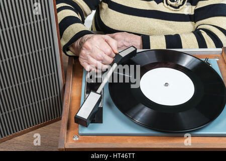 Old woman player includes, dropping the needle on the disc, close-up Stock Photo