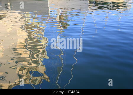 Abstract reflections of boats and buildings in blue rippled water Stock Photo