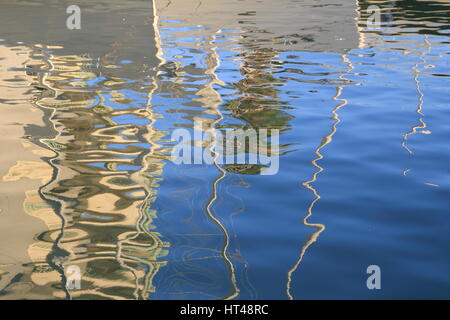 Abstract reflections of boats and buildings in blue rippled water Stock Photo