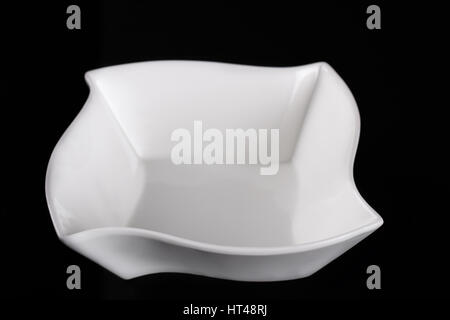 Deep porcelain dish. White bowl on black background Stock Photo