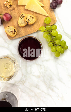 An overhead photo of a wine and cheese tasting, with bread, grapes, glasses of red and white wine, and a place for text Stock Photo
