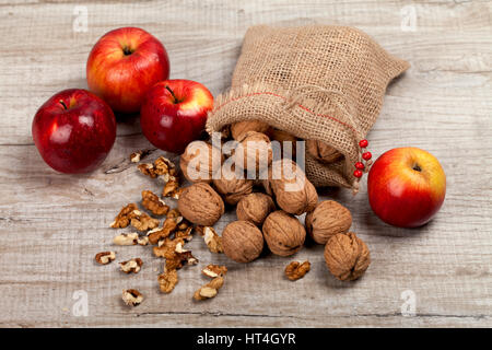 Whole walnuts, nut kernel and apples on a wooden table Stock Photo