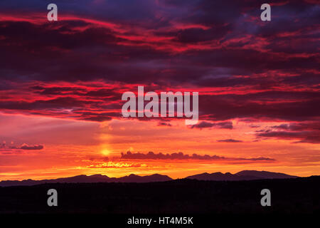 Colorful Arizona desert sunset sky with dramatic clouds and sun pillar near Bylas Stock Photo