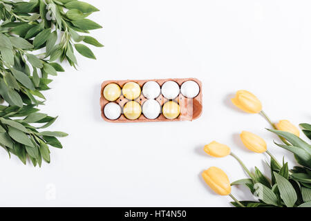 Painted Easter eggs and yellow tulips on white background, top view Stock Photo