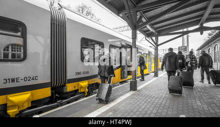 Szklarska Poreba, Poland -  February 2017 :  Tourists with wheeled luggage cases boarding ready to depart local train standing on a platform on the tr Stock Photo