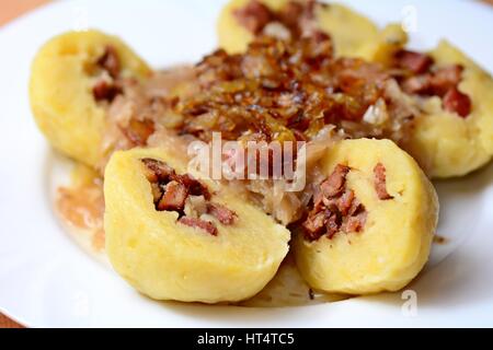 Portion of the sliced traditional czech potato dumplings stuffed with smoked meat, braised cabbage and fried onion. Stock Photo