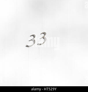 house number in stainless steel numbers, 33 on a white door Stock Photo