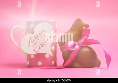 Happy Easter pink polka dot coffee mug with chocolate bunny, with faded lens flare filter. Stock Photo