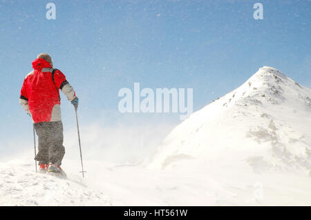 Climber facing wind and snow on mountain summit Stock Photo