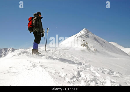 Climber facing wind and snow on mountain summit Stock Photo