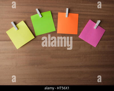 Four Post It notes displayed in an arc on small pegs, layed out on softly grained wood Stock Photo