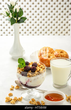 Delicious and healthy breakfast of granola, buns brioche, honey and milk on a light background. Soft focus. Stock Photo