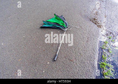 Discarded broken umbrella laying on the ground. Stock Photo