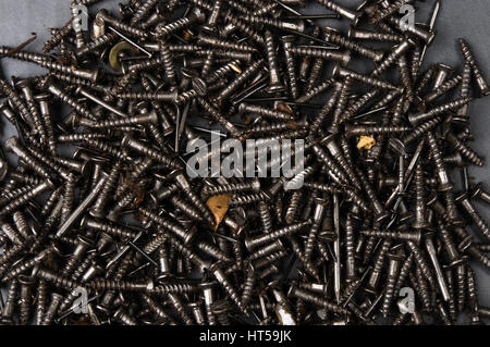 techno backgrounds - black oiled Bunch of screws on a dark grey cardboard Stock Photo