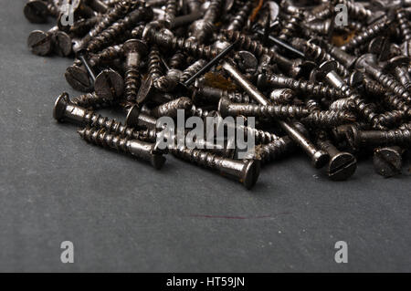 techno backgrounds - black oiled Bunch of screws on a dark grey cardboard Stock Photo