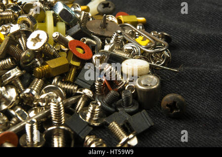 techno backgrounds - various bolts, screws, washers, nuts and other computer small fasteners on black fabric Stock Photo