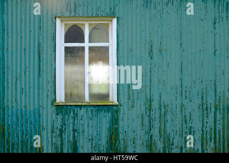 window on green painted corrugated iron church wall Stock Photo