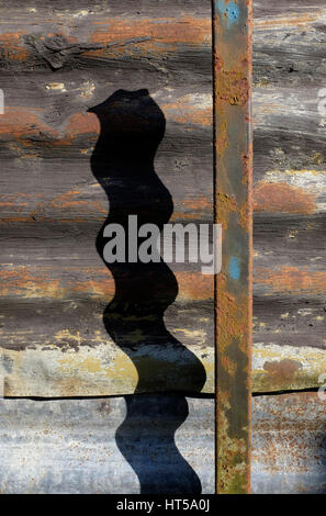 shadow of metal pole on corrugated iron shed wall Stock Photo
