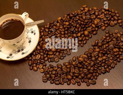 A cup of coffee and coffee beans like one big bean on the table. Stock Photo