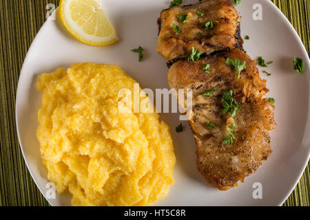 Fried mackerel with polenta and lemon on plate Stock Photo