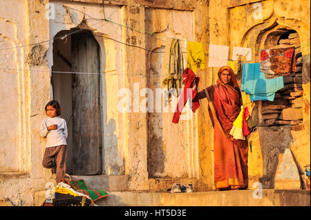 A woman hanging washing on the line outside her home in Orchha, India Stock Photo