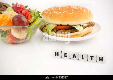 Health word on dices. Hamburger and fruits in babkground Stock Photo