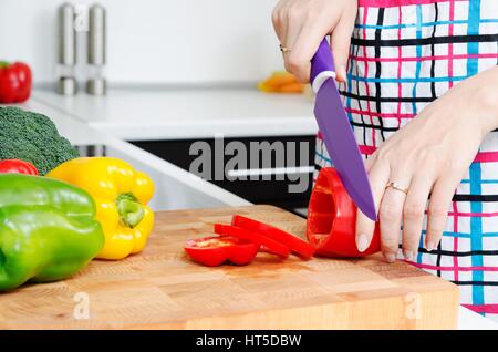 Woman chef cutting peppers. Food preparation in modern kitchen Stock Photo